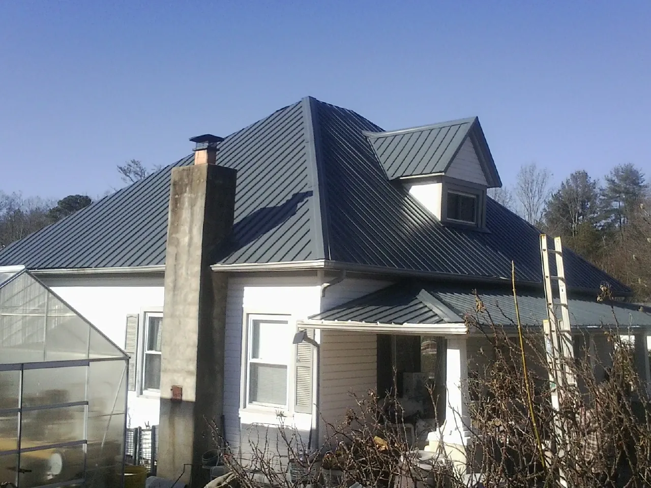Dark blue standing seam metal roof on a white farmhouse with dormer — Slate & Tile Roof Repair by Roofing Brothers in Everett